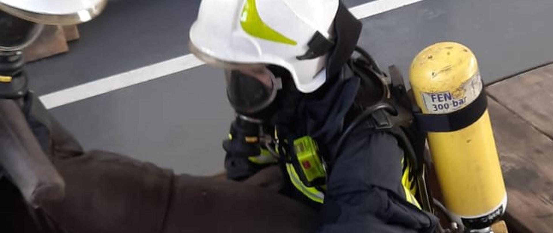 Fotografia przedstawia strażaków OSP podczas ćwiczeń. Strażacy w ubraniach specjalnych i sprzęcie OUO niosą manekina. 