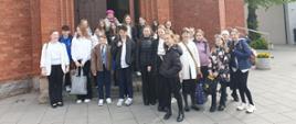 Na zdjęciu grupa uczniów. Wszyscy stoją na chodniku przed kościołem. 