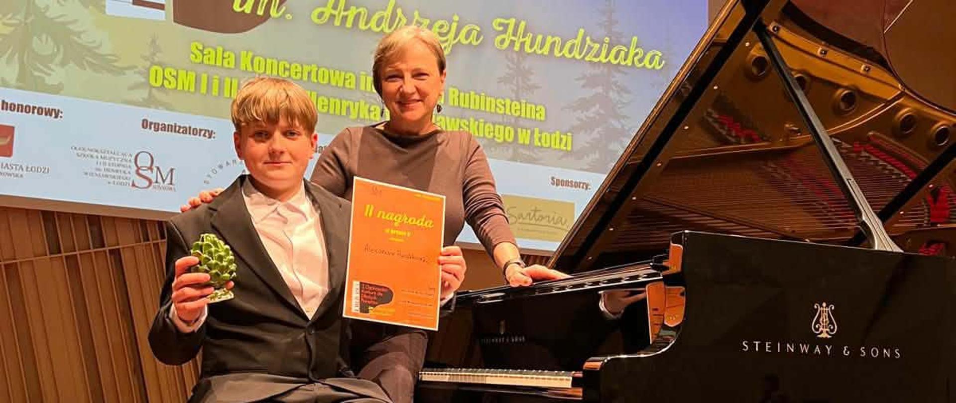 Elżbieta Lieder pozuje przy fortepianie podczas konkursu w Łodzi wraz ze swoim uczniem Alexandrem Pawlikowskim