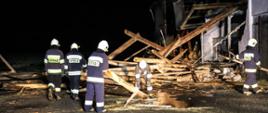 Zdjęcie przedstawia strażaków, którzy usuwają drewniane elementy konstrukcyjne stodoły.