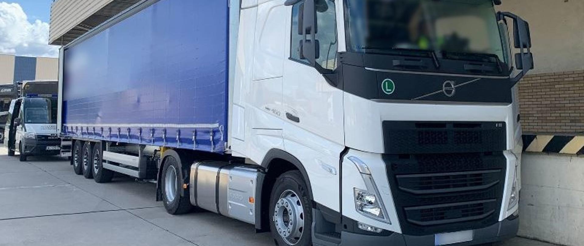 Na pierwszym planie zestaw ciężarowy kontrolowany przez patrol lubuskiej ITD. Za ciężarówką stoi oznakowany radiowóz lubuskiej ITD typu furgon.