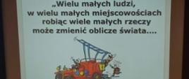 Widok z przodu. Slajd prezentacji wyświetlony na ekranie. Centralnie pojazd strażacki, na górze napis "Wielu małych ludzi, w wielu małych miejscowościach robiąc wiele małych rzeczy może zmienić oblicze świata". 