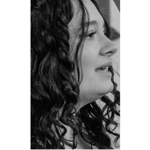 Zdjęcie czarnobiałe. Twarz dziewczyny z profilu. Kręcone czarne włosy.