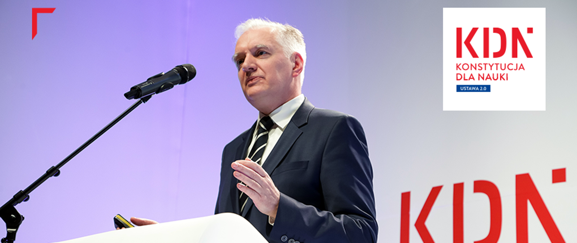 Minister Gowin przemawia do mikrofonu, w tle ściana z logiem KDN