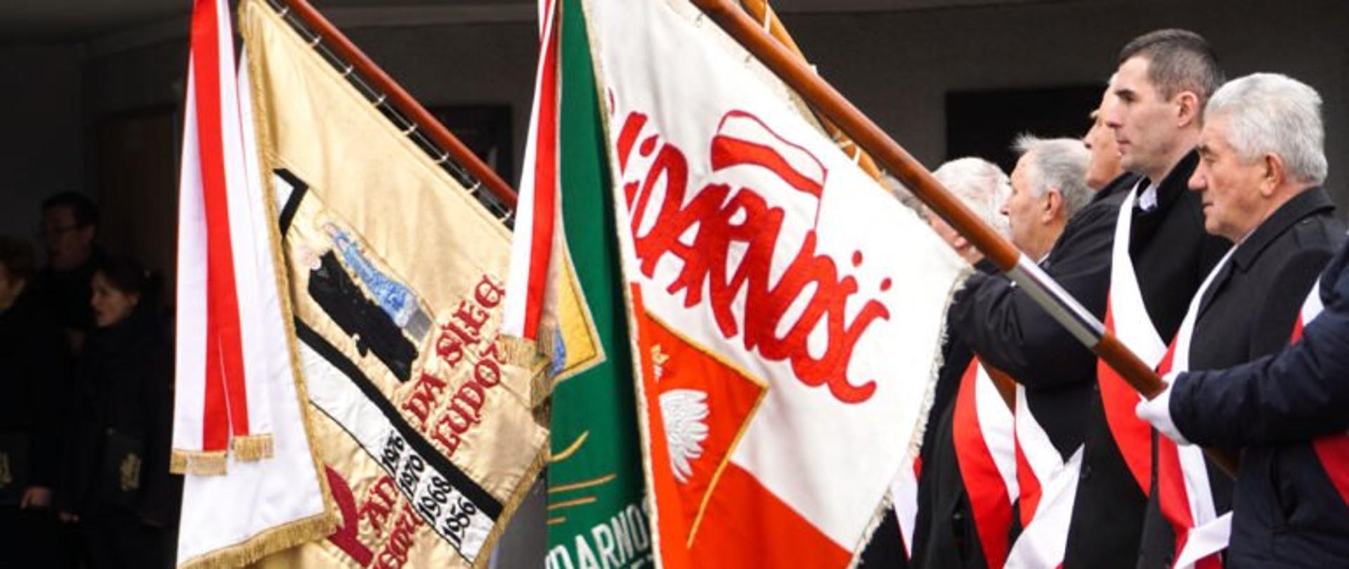 Mężczyźni trzymający sztandary podczas uroczystości w 42.rocznicę Porozumień Rzeszowsko-Ustrzyckich