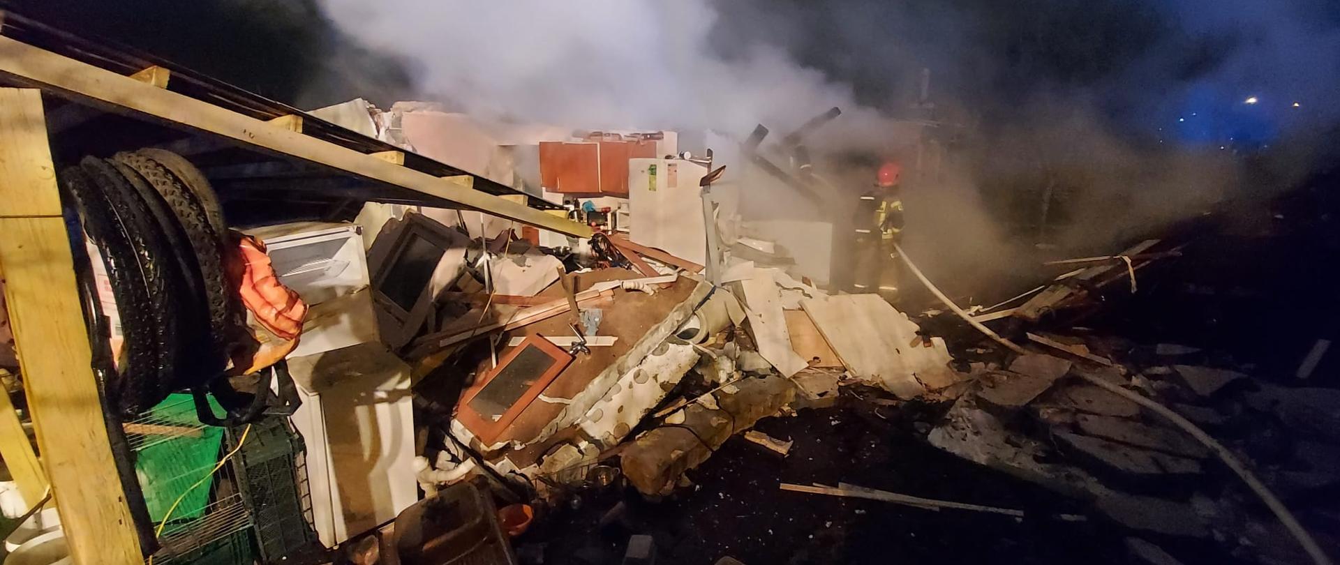 Zdjęcie przedstawia strażaków gaszących palącą się altanę