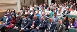 Na auli znajduje się kilkadziesiąt osób, które siedząc na krzesłach z uwagą słuchają wygłaszanych prelekcji.