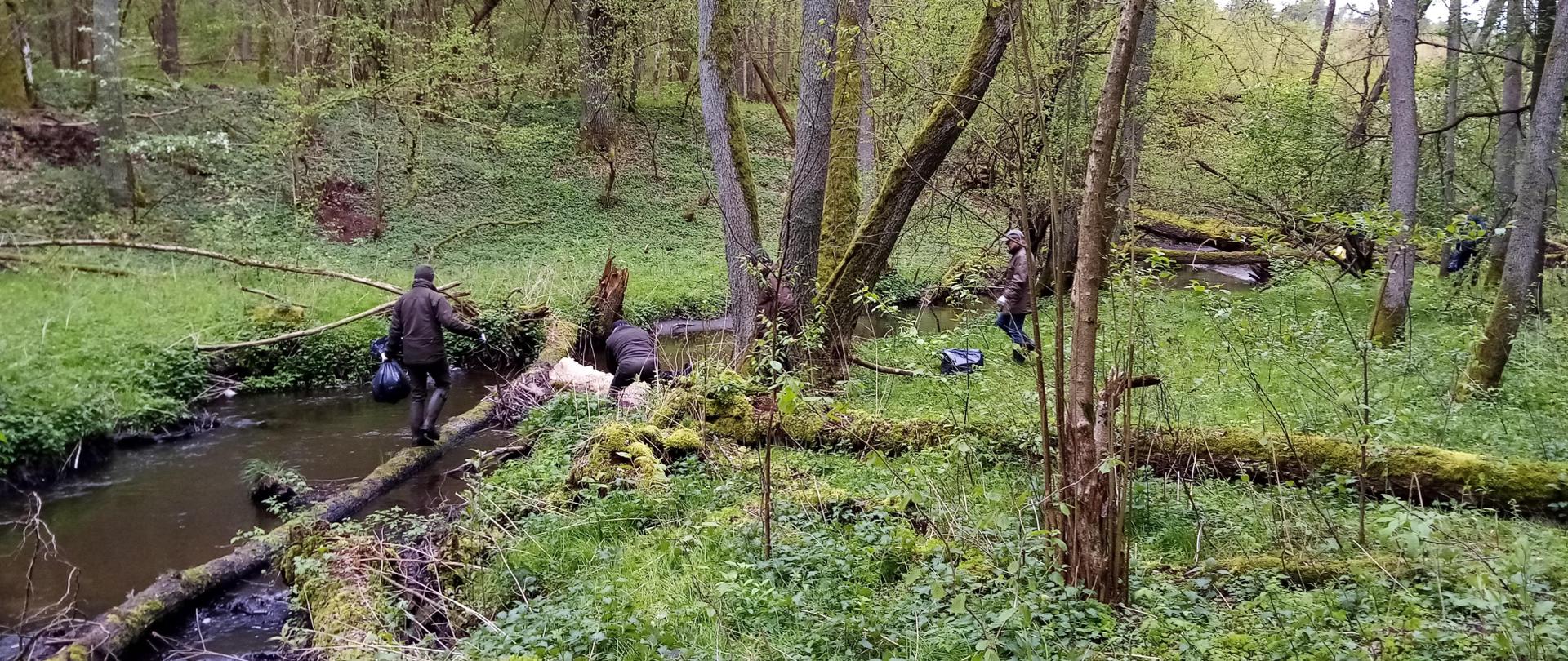 Trzech mężczyzn z workami na odpady nad brzegiem rzeki