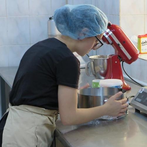 Kobieta w kuchni przy maszynie do ubijania ciasta i wadze spożywczej.