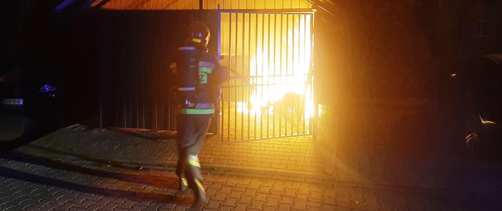 Strażak gasi pożar śmietnika