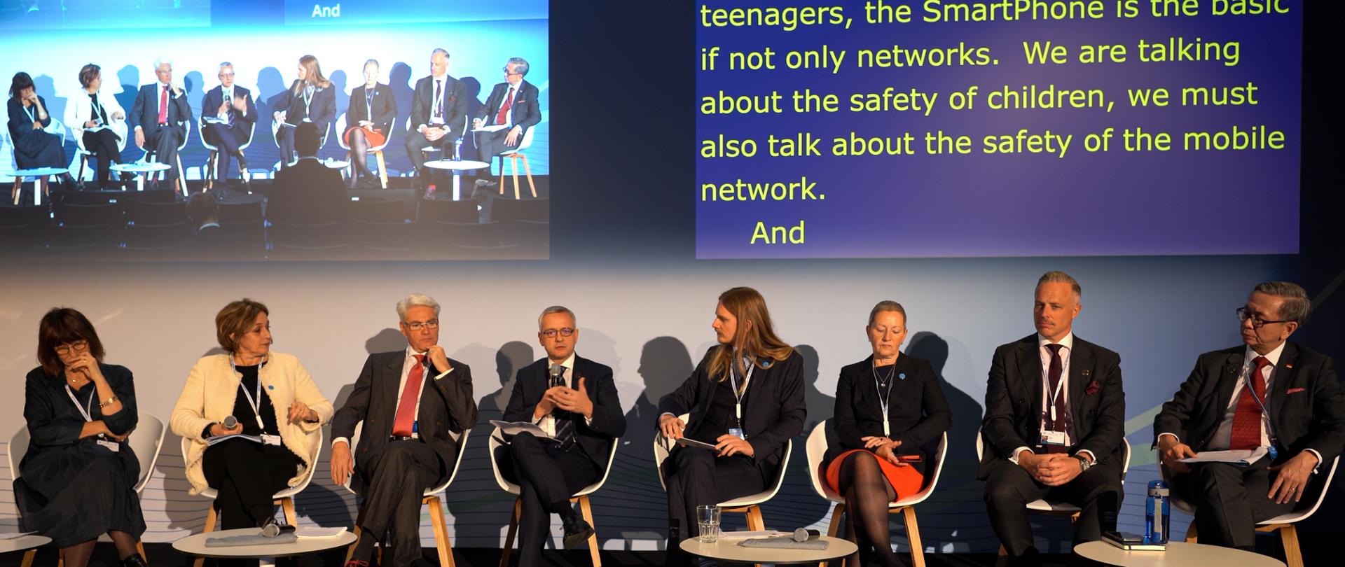 Sala konferencyjna - na scenie ośmioro uczestników panelu. Po środku minister Marek Zagórski mówiący do mikrofonu. W tle dwa ekrany.