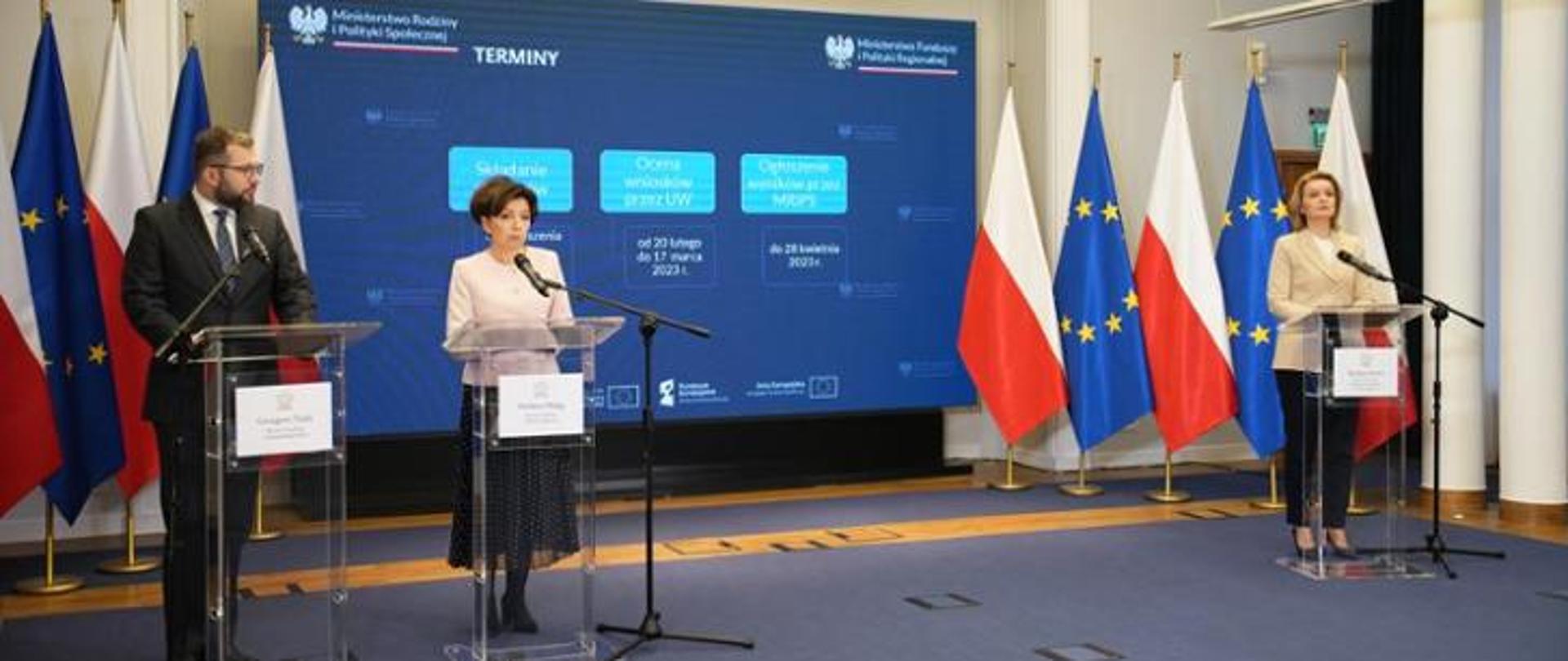 Trzy osoby stojące przy mównicach i wypowiadające się 