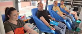 Zdjęcie przedstawia druhów OSP podczas oddawania krwi, którzy siedzą w krwiobusie