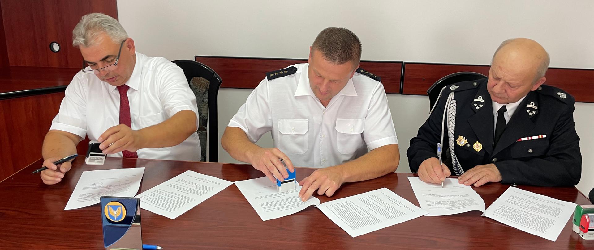 Na zdjęciu przedstawiciele instytucji podpisują przy biurku porozumienie