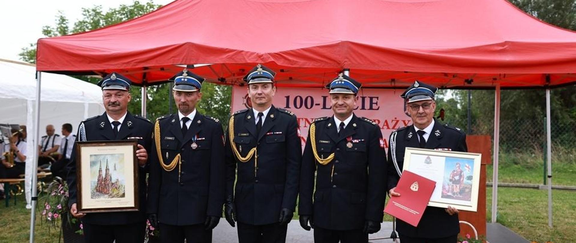 Komendant Powiatowy PSP w Ciechanowie, Zastępca Komendanta, Mazowiecki Komendant Wojewódzki PSP a także druhowie z jednostki OSP z obrazami, które są prezentem na 100-lecie. 