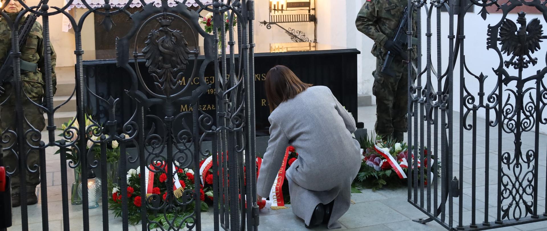 kobieta kładzie kwiaty na grobie marszałka sejmu