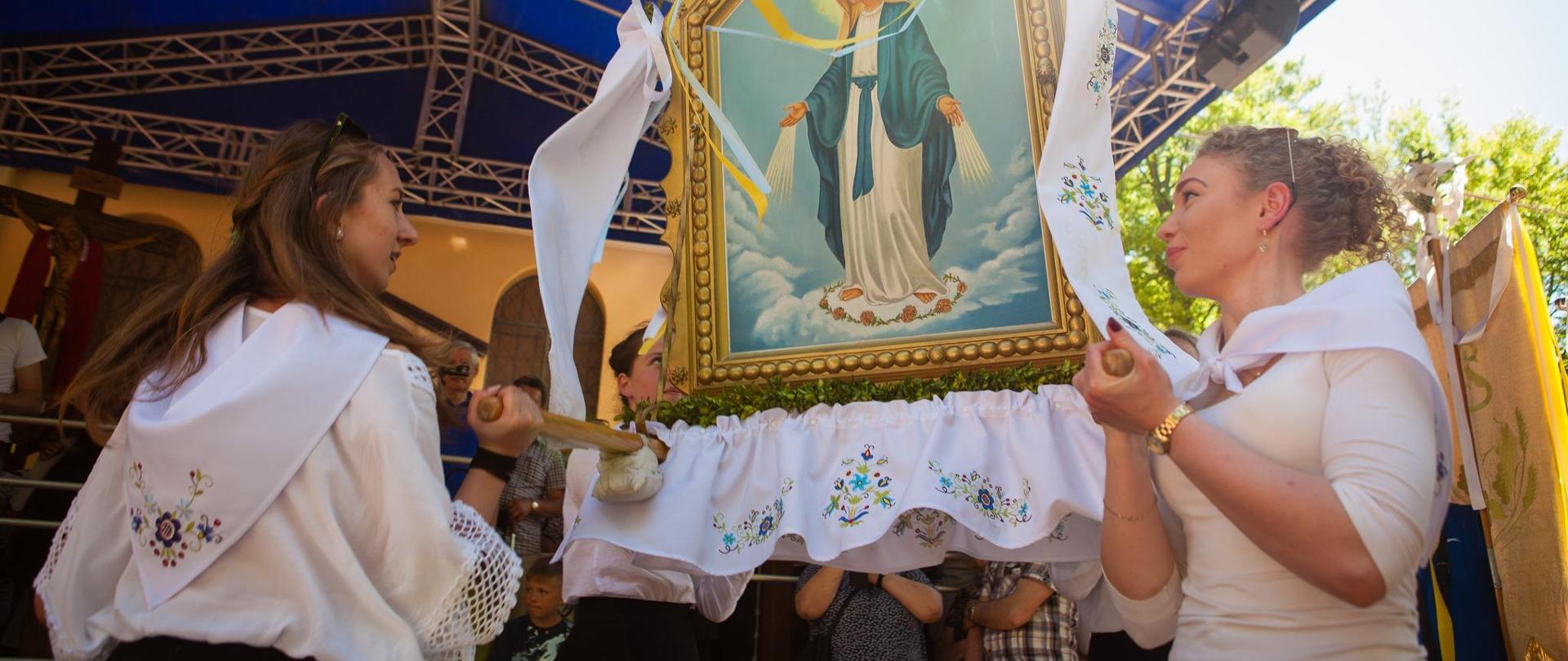 Dwie kobiety w kaszubskich strojach trzymają obraz 