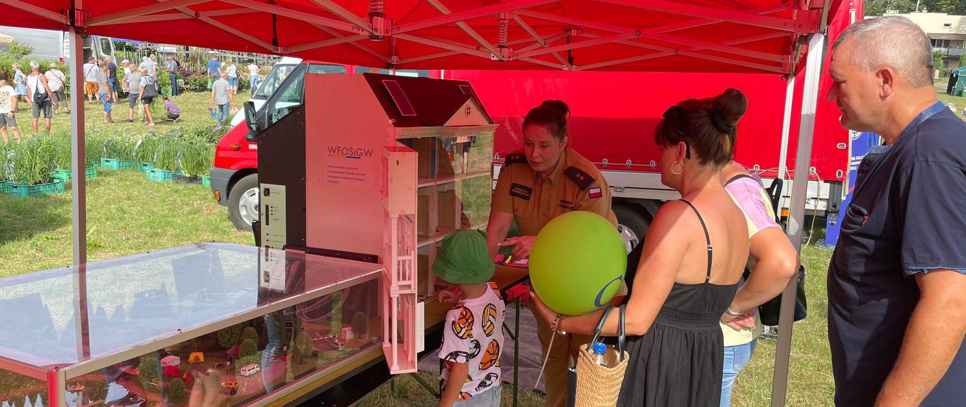 Zdjęcie przedstawia pokaz symulatora zagrożeń pożarowych domku jednorodzinnego dla dzieci i dorosłych podczas targów rolniczych Kościelec 2024