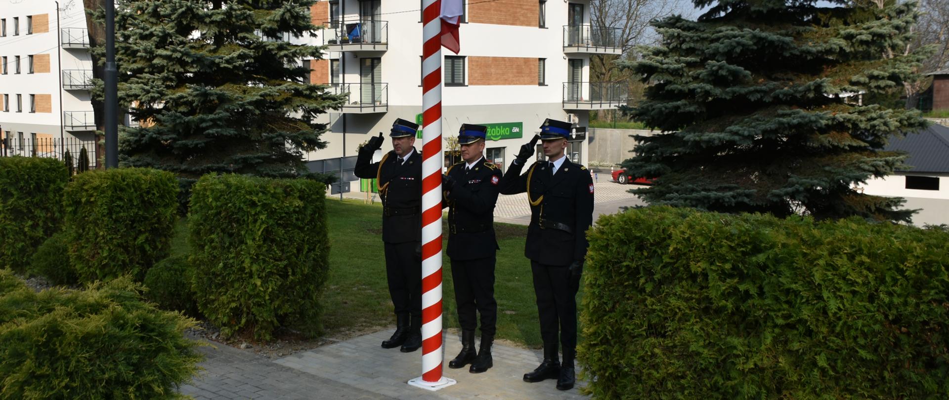 Zdjęcie przedstawia uroczyste podniesienie flagi państwowej na maszt z okazji Dnia Flagi. Podniesienia flagi dokonuje poczet flagowy. 