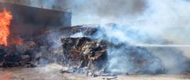 Zdjęcie przedstawia palące się baloty sprasowanej makulatury, trwają działania gaśnicze