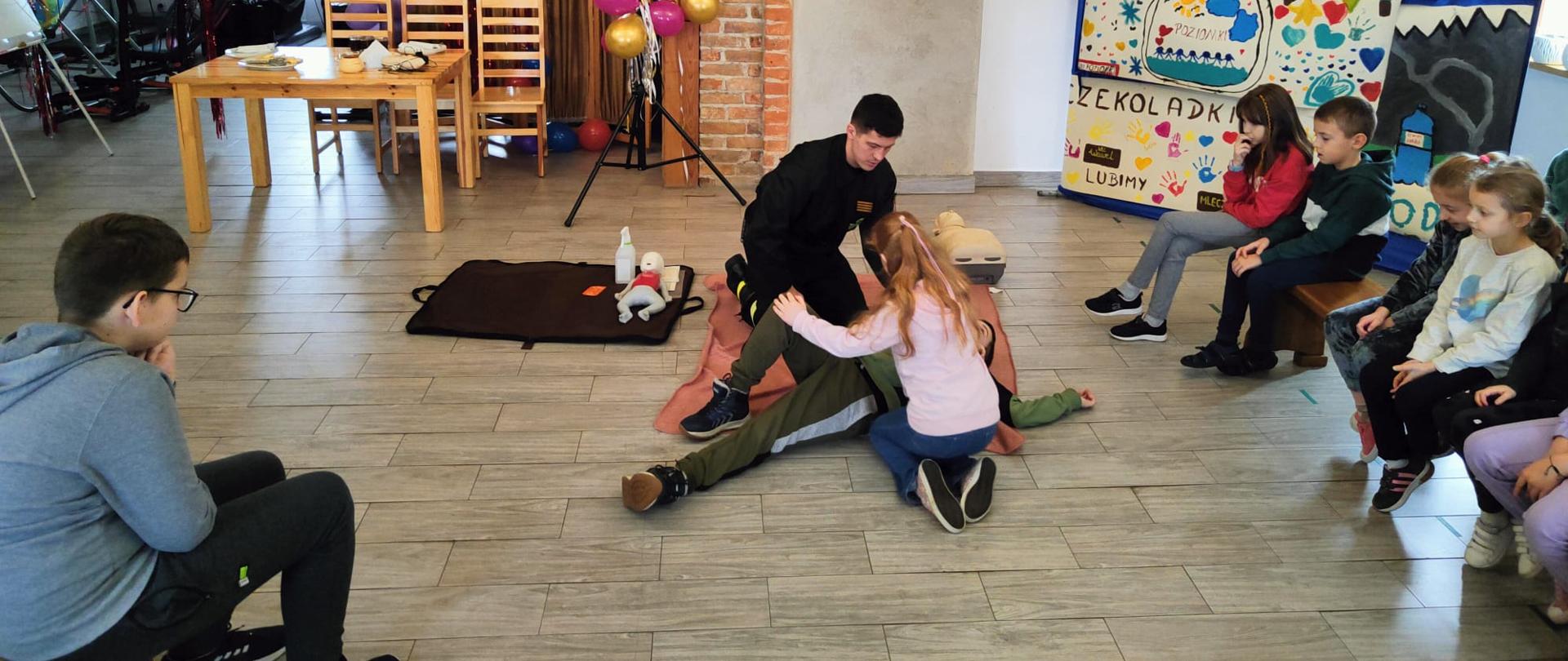 Zdjęcie przedstawia ćwiczenia pierwszej pomocy przez dzieci uczestniczące w półkoloniach zimowych 