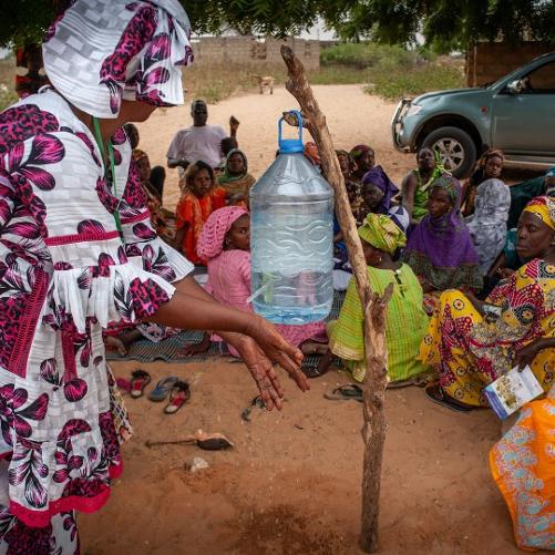 Grupa kobiet siedzi i patrzy jak inna myje ręce