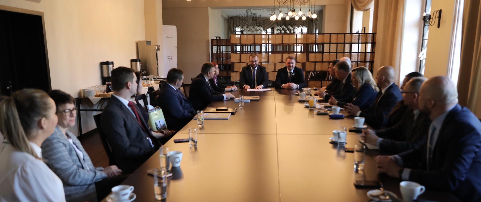 uczestnicy spotkania przy stole konferencyjnym, na szycie stołu po lewej minister Grzegorz Puda