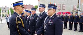 Widok z boku. Zastępca małopolskiego komendanta wojewódzkiego PSP w trakcie dekoracji strażaków OSP odznaczeniami resortowymi.