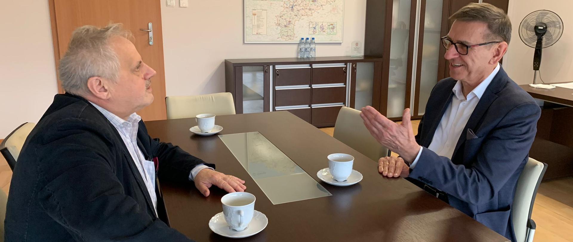 Dwóch mężczyzn siedzi przy stole 