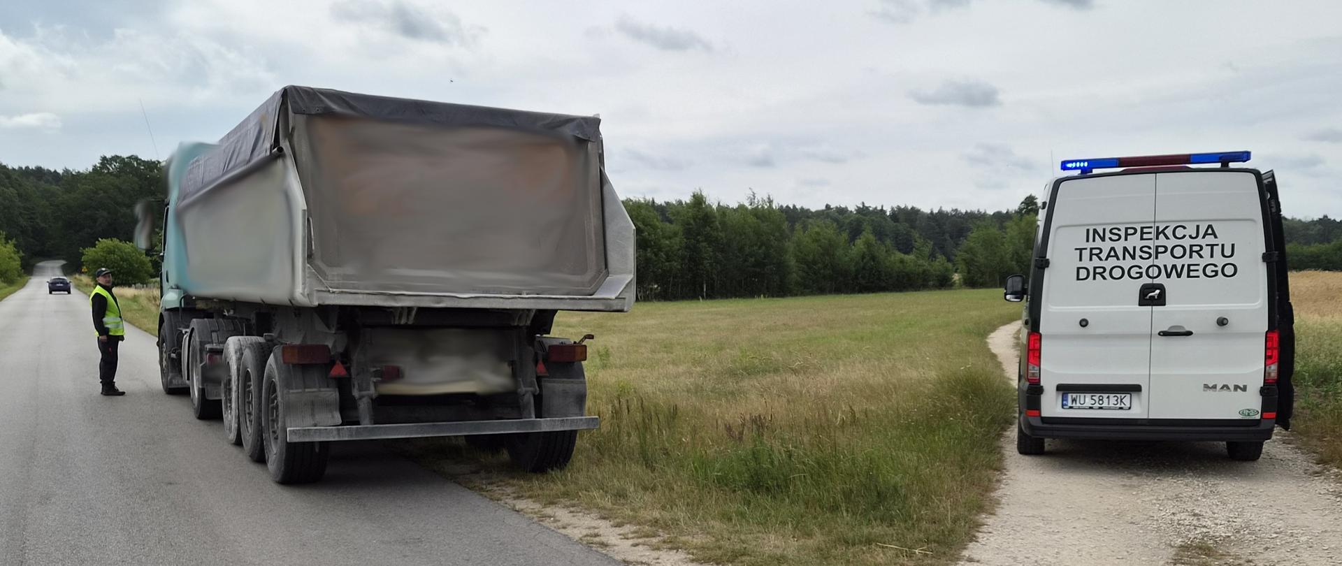 Zatrzymana ciężarówka z naczepą, obok której stoi inspektor. Obok stoi oznakowany radiowóz ITD.