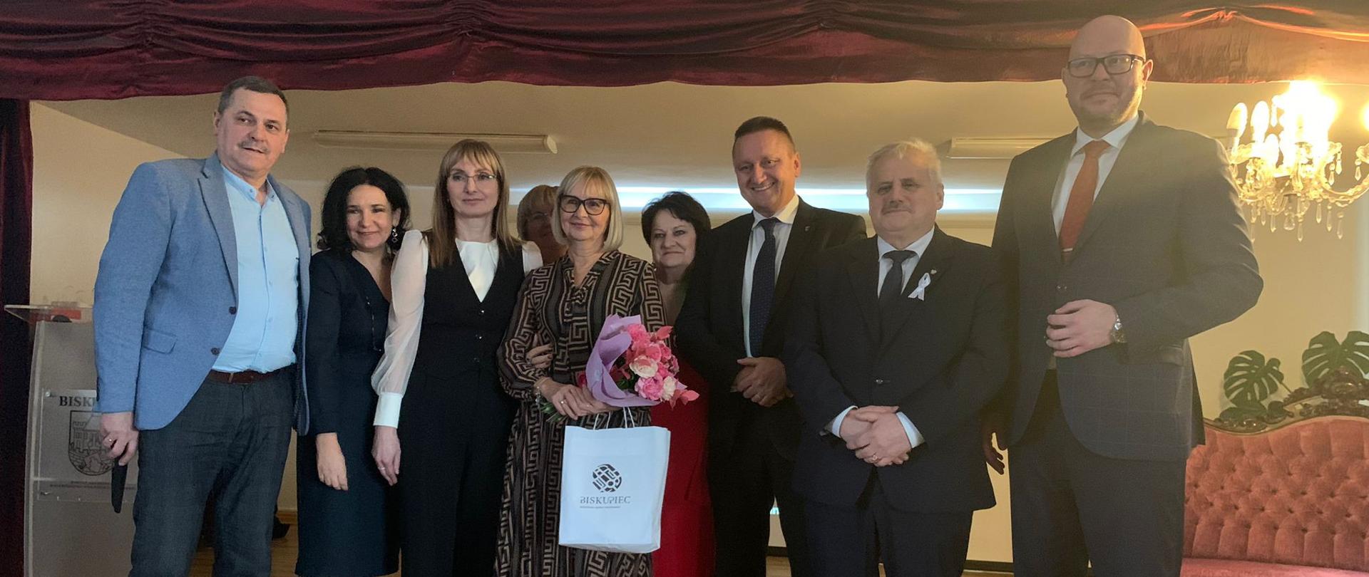 Kilkanaście osób stoi na scenie. 