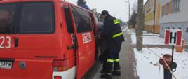 Strażacy pomagają wejść do samochodu pozarniczego starszej osobie, celem przewieziania na szczepienia