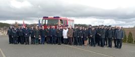 Zdjęcie grupowe z uroczystości przekazania. W tle wóz strażacki 