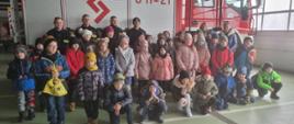 Wizyta w ramach akcji „Odwiedź strażnicę i salę edukacyjną typu Ognik” w KP PSP w Sokołowie Podlaskim - na zdjęciu dzieci i strażacy stoją w garażu JRG.