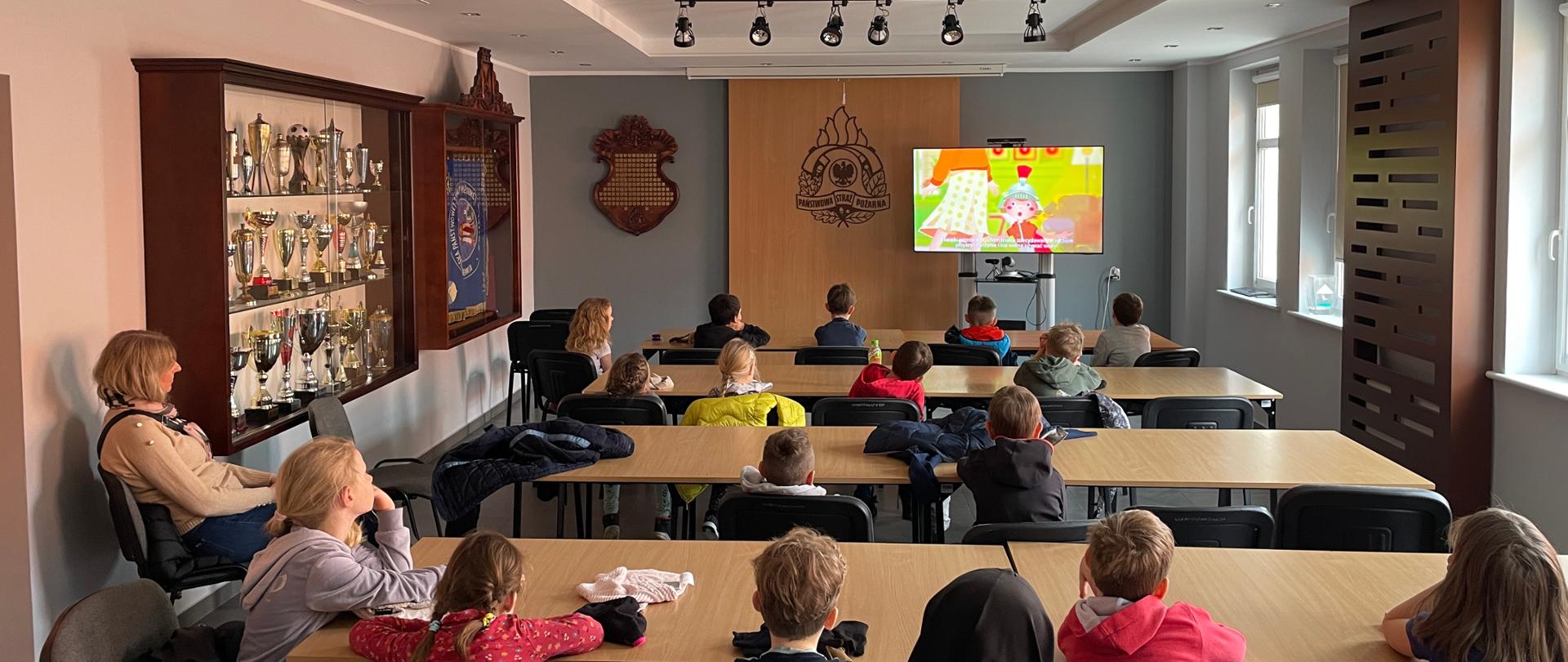 Świetlica Komendy w Sopocie. Dzieci siedzą w ławkach wraz z Panią i oglądają bajkę o tym jak zachować się podczas pożaru