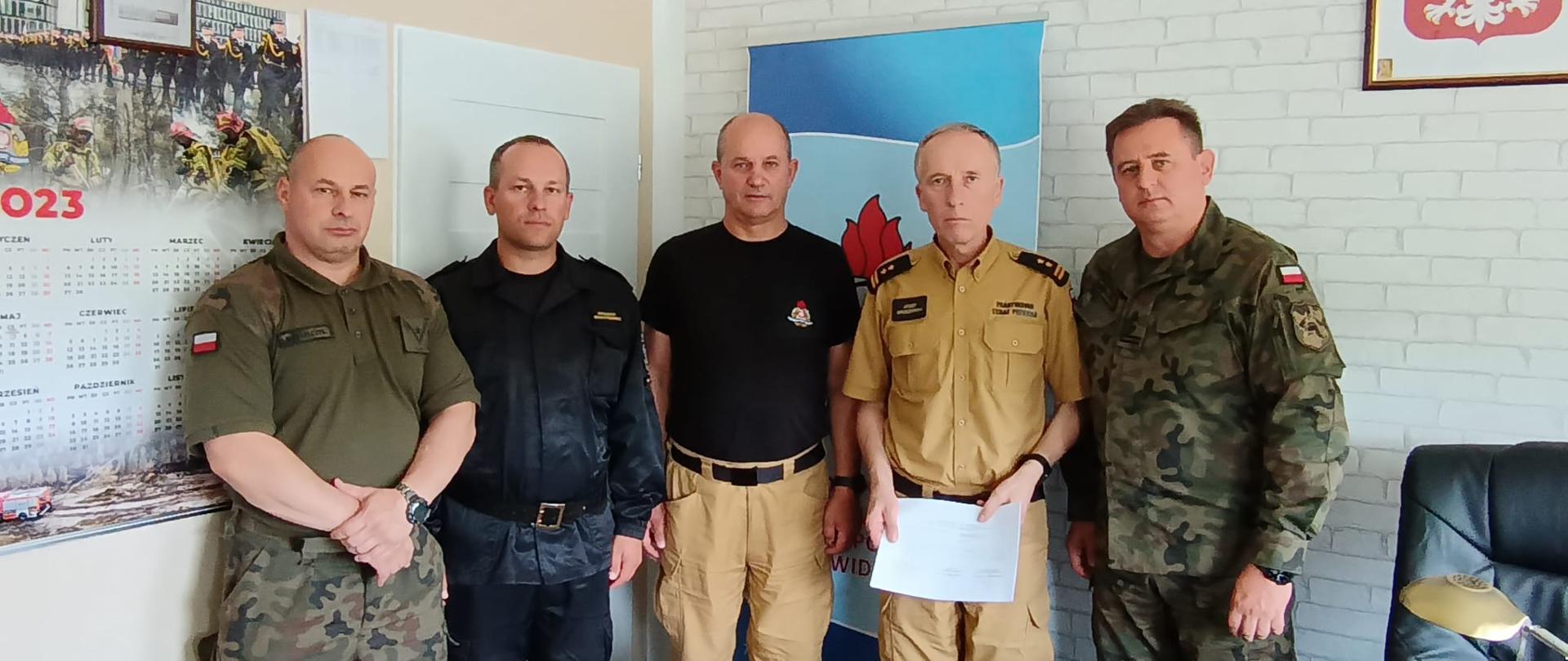 Zdjęcie przedstawia 5 mężczyzn podczas spotkania operacyjnego w biurze komendanta.
