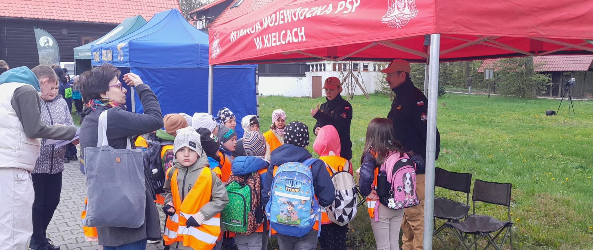 Zdjęcie przedstawia stoisko Państwowej Straży Pożarnej, przy którym stoją uczniowie słuchający prelegenta.