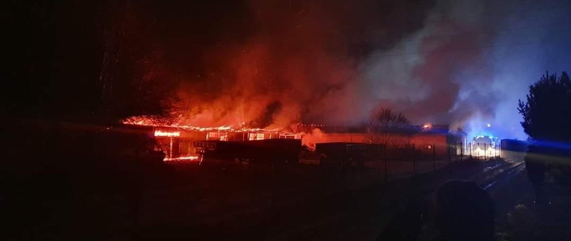 widok początku akcji gaśniczej, budynek w całości objęty pożarem, na miejsce przyjeżdżają pierwsze zastępy