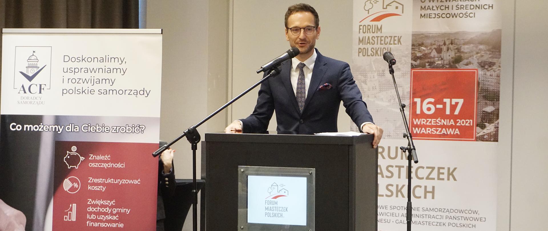 W mównicy na tle banerów przemawia Waldemar Buda