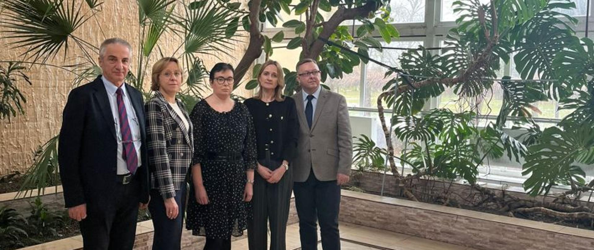 Pięć osób pozuje do zdjęcia stojąc w palmiarni