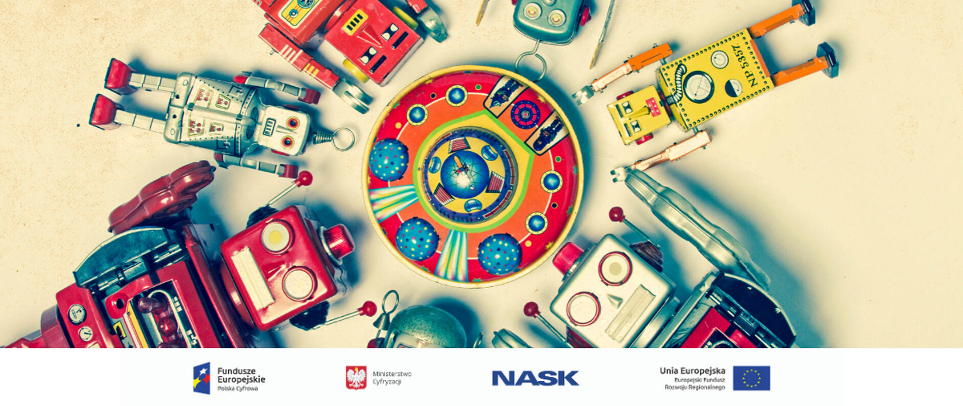 Na zdjęciu widać kilka różnych zabawek-robotów z rękami uniesionymi do góry, ułożone koncentrycznie na płaskiej powierzchni. U dołu znajduje się pasek logotypów: Europejskie Fundusze Polska Cyfrowa, Ministerstwo Cyfryzacji, NASK i Unia Europejska Europejski Fundusz Rozwoju Regionalnego.