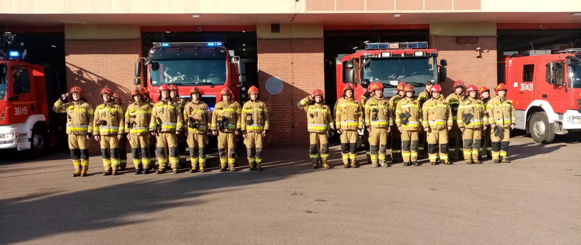 Minuta ciszy dla poległych strażaków z Ukrainy. Strażacy przed KM PSP w Łomży oddają hołd poległym strażakom na Ukrainie stojąc na baczność. Dowódca salutuje.