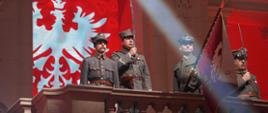 widowisko, żołnierze stoją na balkonie, w tle na czerwonym materiale biały orzeł