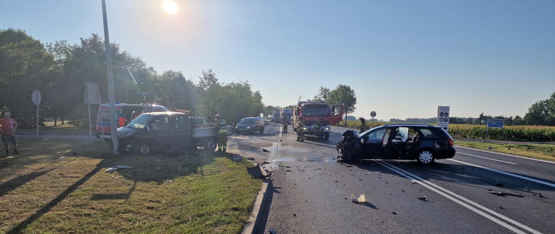 Wypadek drogowy na obwodnicy Brzegu - zdjęcie przedstawia rozbity samochód osobowy oraz samochód dostawczy, w tle samochód pożarniczy oraz karetka pogotowia