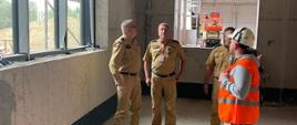 Z-ca Komendanta Głównego PSP, Łódzki Komendant Wojewódzki PSP i Zastępca Komendanta Miejskiego PSP w Łodzi na terenie budowy wewnątrz budynku , z nimi mężczyzna w pomarańczowej kamizelce i kasku