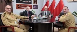 Zastępca komendanta głównego, dyrektor biura edukacji oraz dwóch mężczyzn z PKP Polskie Linie Kolejowe S.A siedzących przy stole prezydialnym w gabinecie komendanta. 