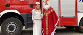 Mikołaj wraz kobieta przebraną za anioła na tle wozu strażackiego 