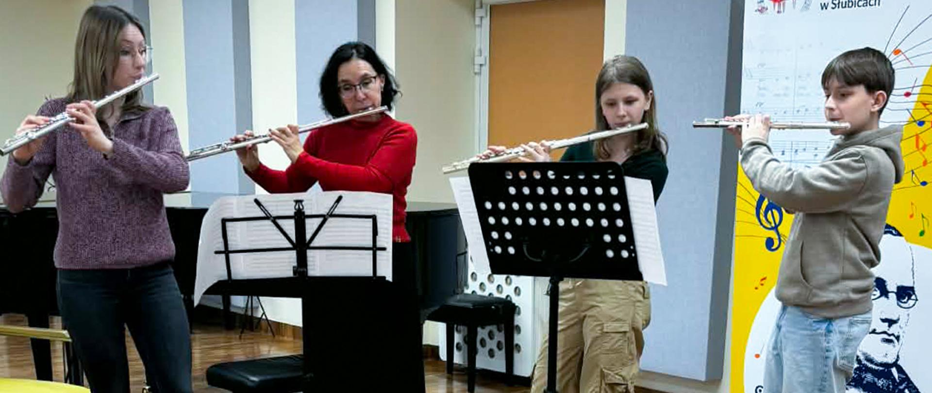 Dwie nauczycielki i dwoje uczniów grają na fletach poprzecznych.