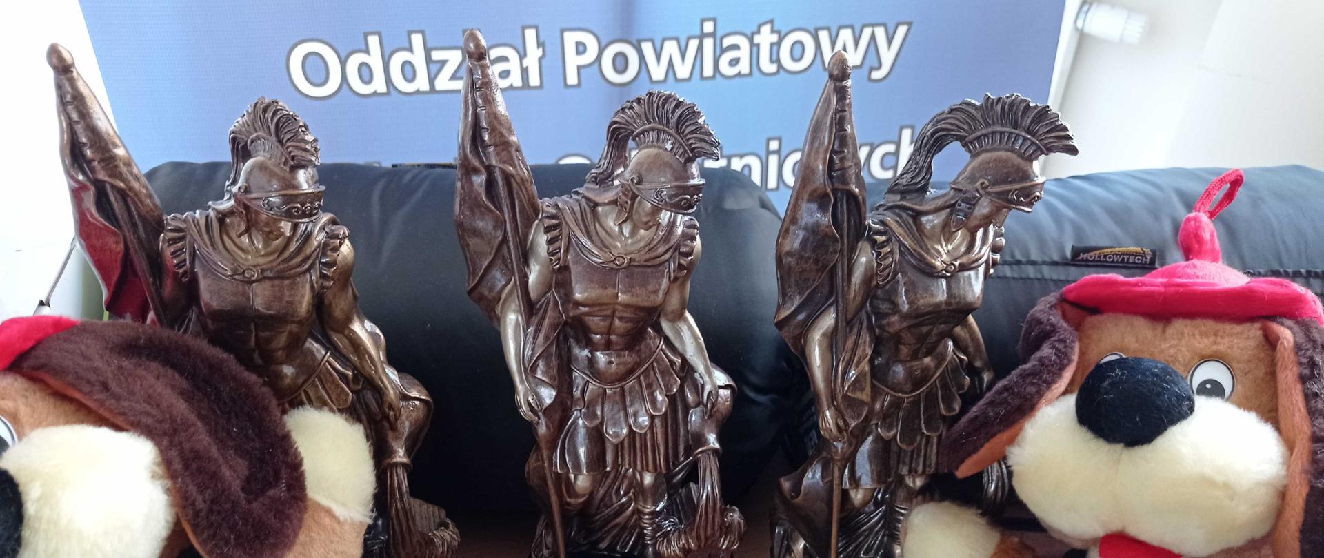 Zdjęcie przedstawia statuetki Turnieju Wiedzy Pożarniczej.
W tle baner Zarządu Powiatowego Związku Ochotniczych Straży Pożarnych RP w Chodzieży.
