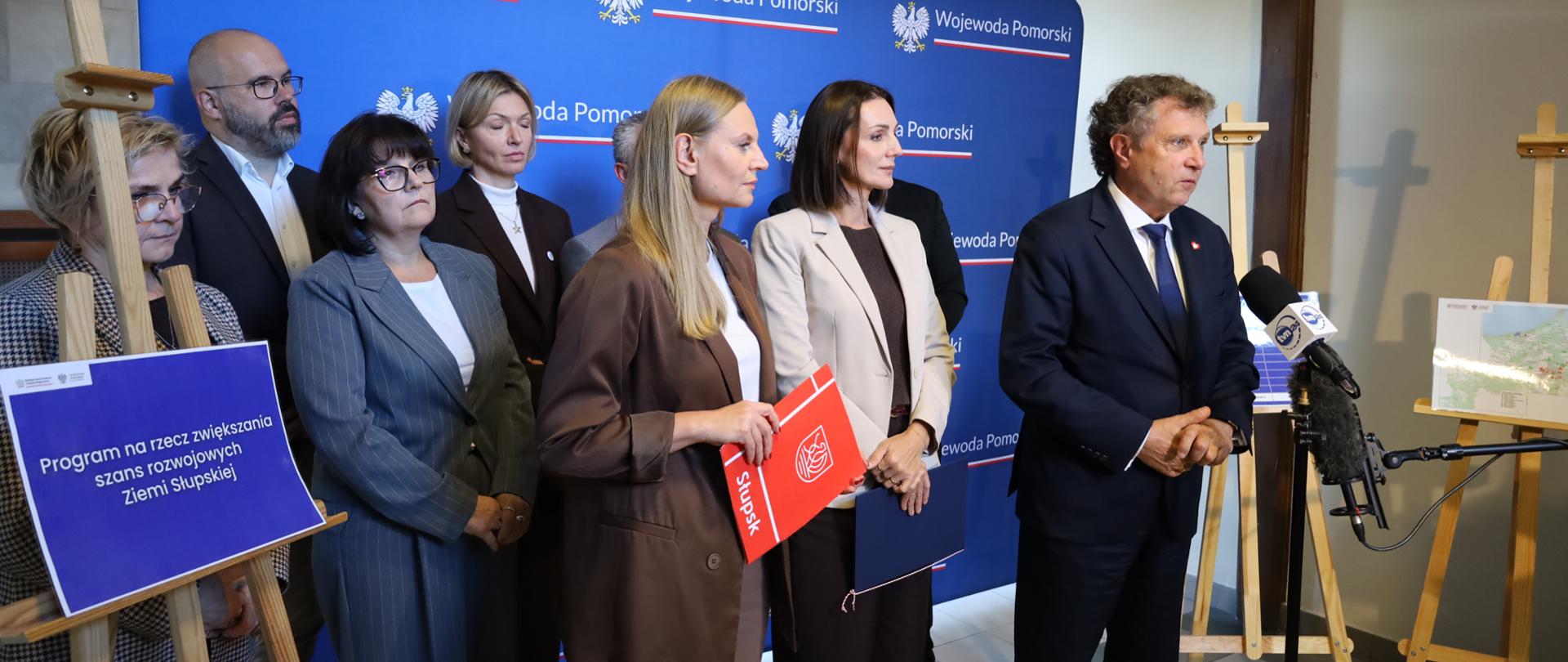 kilka osób stoi na tle baneru z napisem Wojewoda Pomorski, jedna osoba - mężczyzna przemawia 